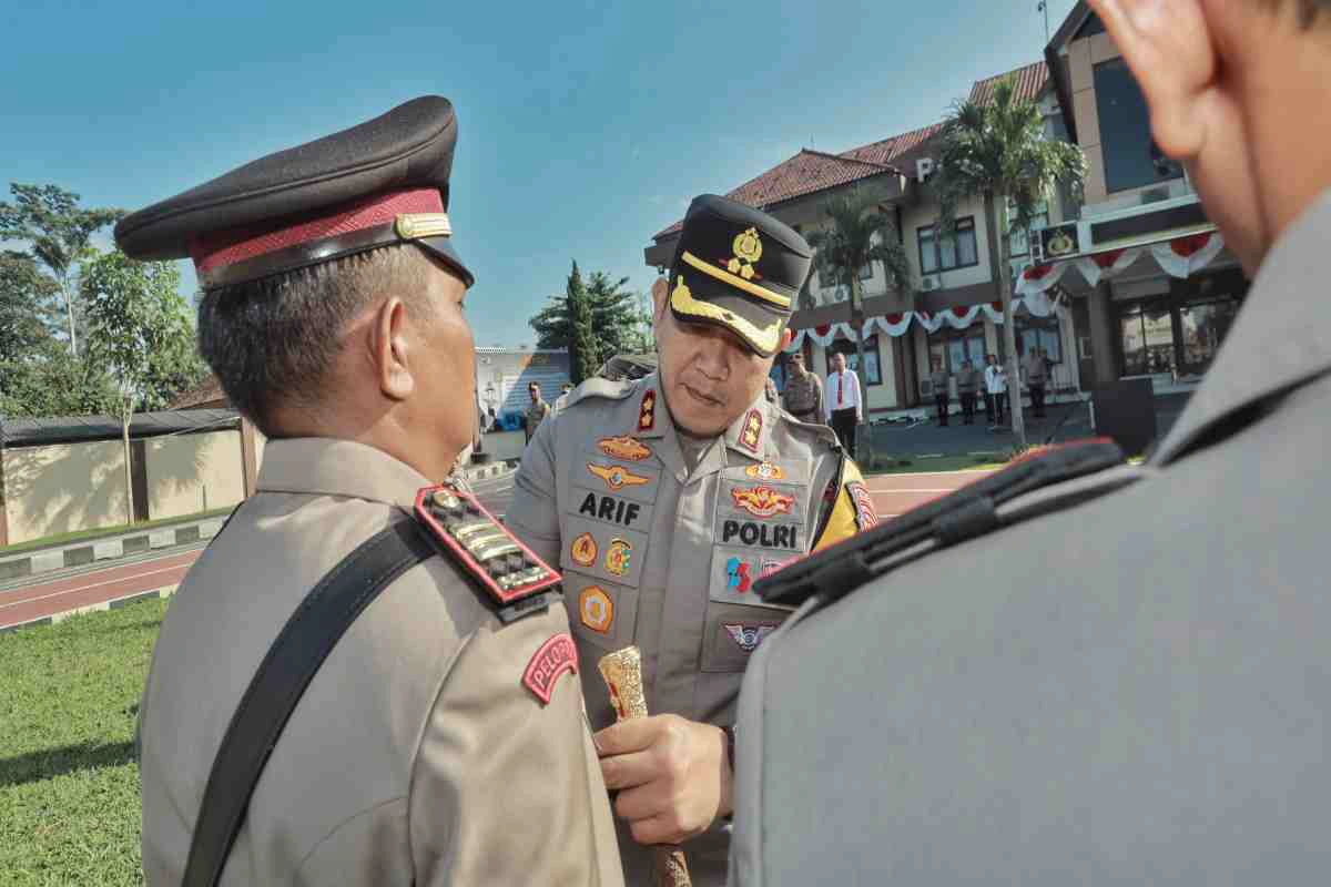 Kapolres Blitar, AKBP Arif Fazlurrahman, memimpin prosesi serah terima jabatan dengan memberikan sebuah lencana kepada salah satu pejabat baru di halaman Mapolres Blitar, Rabu (16/7/2025).