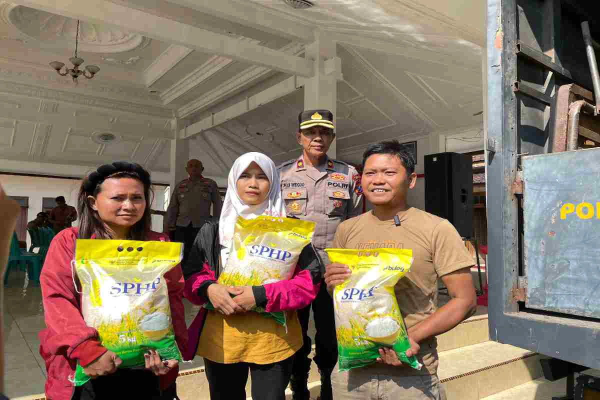 Warga penerima bantuan menunjukkan beras SPHP yang dibagikan Polres Blitar bekerja sama dengan Perum Bulog dalam program Gerakan Pangan Murah di Kabupaten Blitar, Senin (11/8/2025).