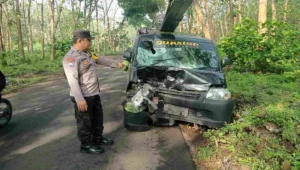Polisi menunjuk bagian depan mobil pick up Daihatsu Grandmax yang ringsek usai terlibat tabrakan adu banteng dengan sepeda motor di Desa Kaulon, Kecamatan Sutojayan, Blitar, Kamis (2/10/2025) pagi.