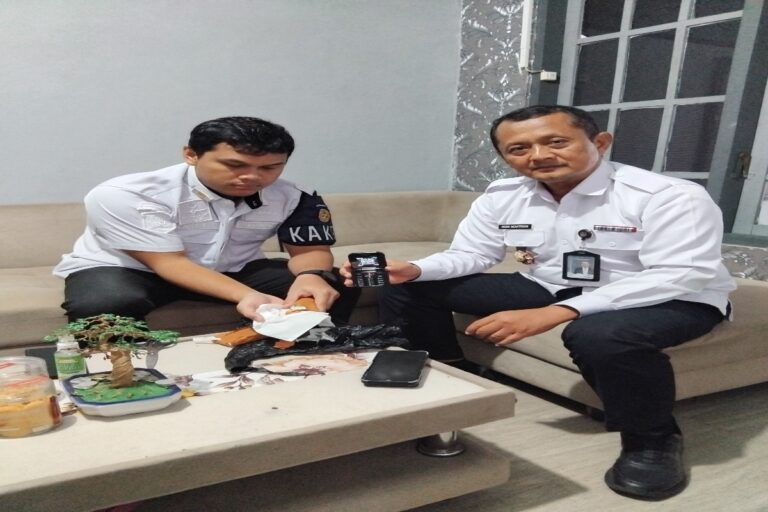 Kepala Lapas Blitar, Romi Novitrion, memeriksa paket berisi handphone dan ratusan pil LL yang berhasil digagalkan sebelum masuk ke dalam lapas, Rabu (18/03).