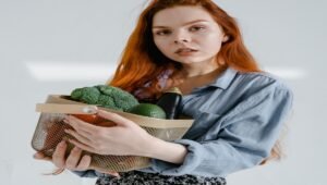 Seorang perempuan memegang buah dan sayuran segar sebagai bagian dari pola makan sehat untuk mendukung kesehatan kulit.