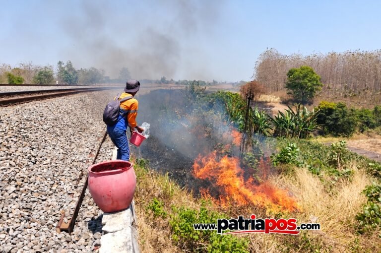 Petugas KAI memadamkan api di sekitar jalur kereta api yang terbakar akibat pembakaran lahan dan ilalang.