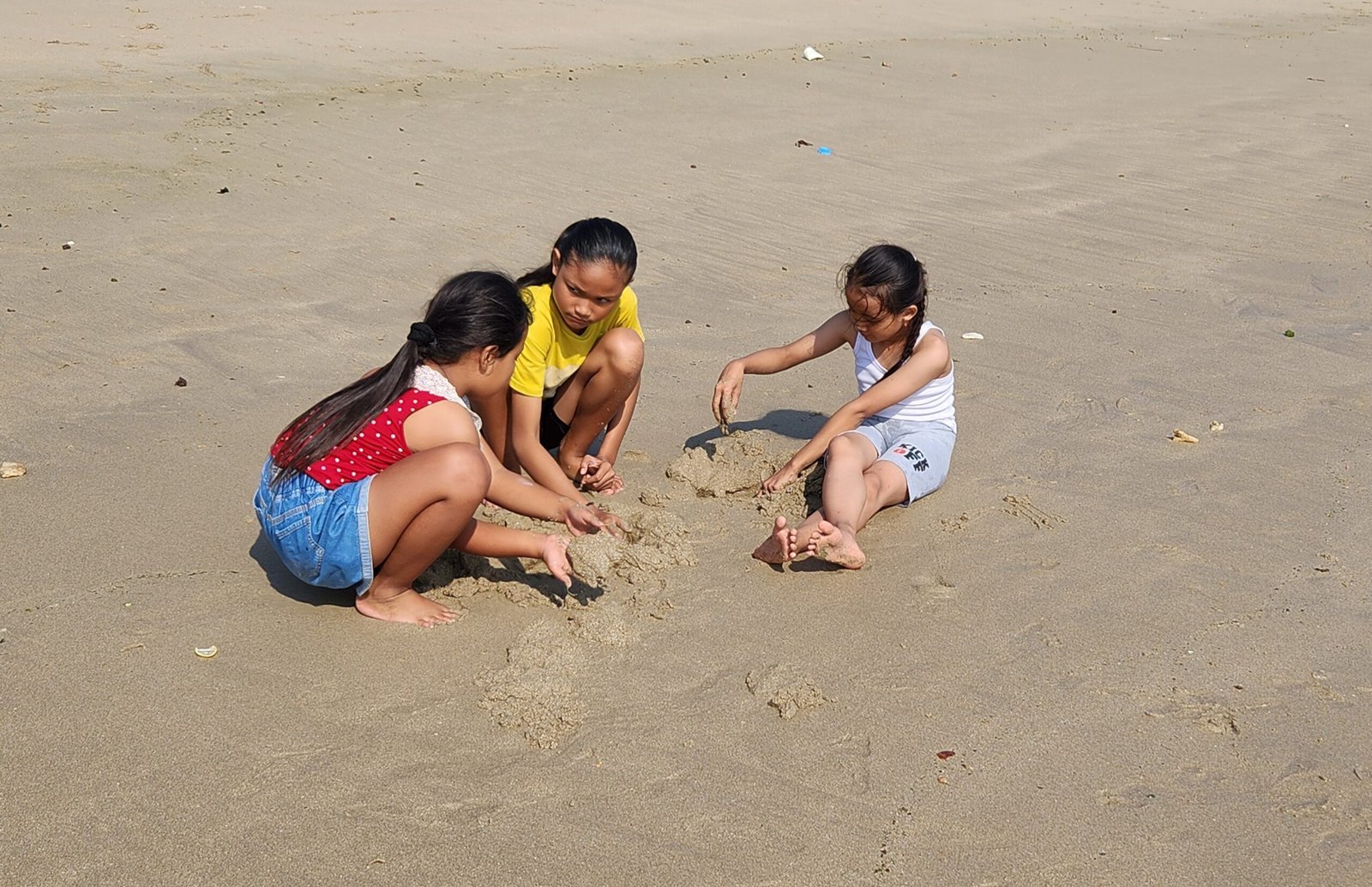 Anak-anak bermain pasir di kawasan Pantai Tambakrejo, Kecamatan Wonotirto, Kabupaten Blitar, saat berwisata bersama keluarga.