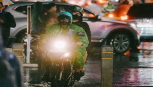 Pengendara sepeda motor melintasi jalan basah saat hujan, ilustrasi prakiraan cuaca Jawa Timur 27 Oktober 2026.